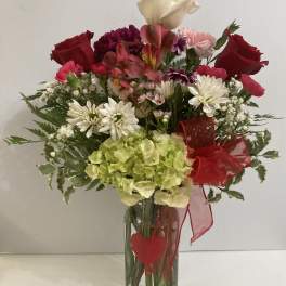 Mixed bouquet in a clear glass vase with red roses and white daisies