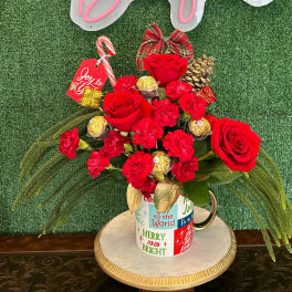 Red roses and carnations in a holiday mug with candy canes and chocolates