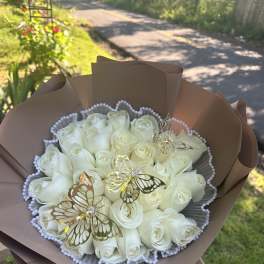Bouquet of white roses wrapped in brown paper with butterfly decorations