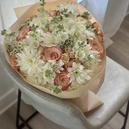 Bouquet of white and peach flowers wrapped in beige paper