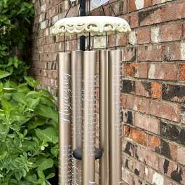 Decorative wind chime with a large white bow and gold tubes