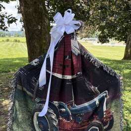 A memorial blanket draped over a stand with a large white bow.