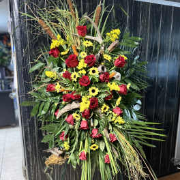 Standing floral spray with red roses and yellow daisies on a wire easel