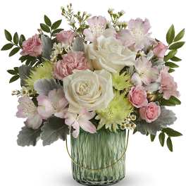 Pink and white flowers arranged in a green glass vase