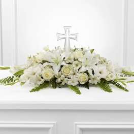 White floral casket spray with a clear cross centerpiece