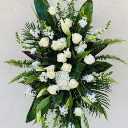 Tall white floral standing spray with roses and lilies on an easel