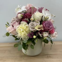 Mixed pink, white, and lavender flowers arranged in a white vase