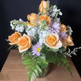 Peach roses and lavender daisies in a glass vase