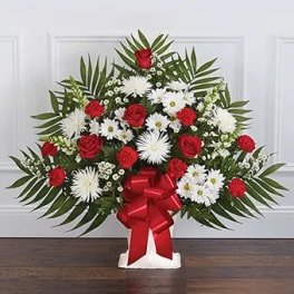 Standing floral spray with red roses, white daisies, and a red bow