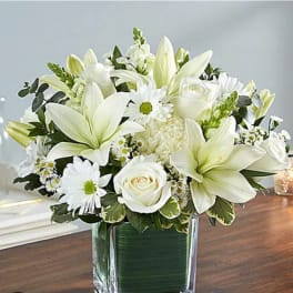 White lilies and roses arranged in a clear glass vase