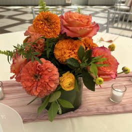 Orange and pink floral centerpiece in a dark vase