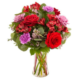 Bouquet of red roses and pink flowers in a clear glass vase