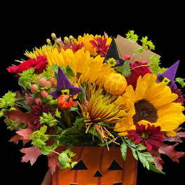 Halloween bouquet in a jack-o'-lantern container with sunflowers and red flowers