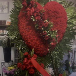 Heart-shaped red floral standing tribute with roses and ribbon