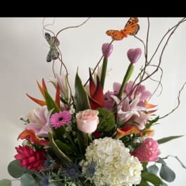 Mixed tropical bouquet in a glass vase with butterfly picks