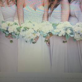 Bridesmaids holding white bouquets with pale blue-green foliage