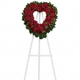 Heart-shaped red rose wreath on a white easel stand