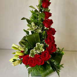 Tall arrangement of red roses and white lilies in a glass vase