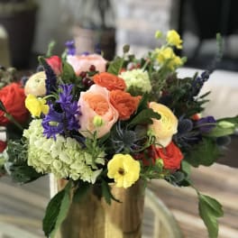 Colorful mixed bouquet in a gold vase with roses and hydrangeas