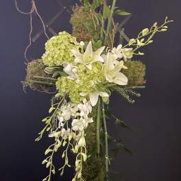 Cross-shaped floral arrangement with white lilies, green hydrangeas, and orchids