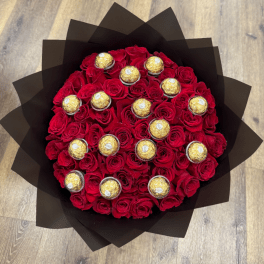 Round bouquet of red roses with gold-wrapped chocolates in black paper wrap