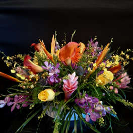 Colorful tropical bouquet with calla lilies, orchids, and roses in a vase