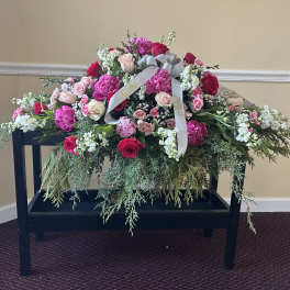 Large pink and white floral spray with roses on a black stand