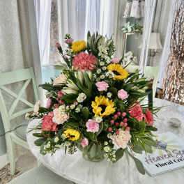 Mixed bouquet with sunflowers, pink carnations, and white daisies in a glass vase