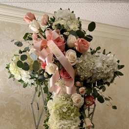 Large cross-shaped floral arrangement with pink and white roses