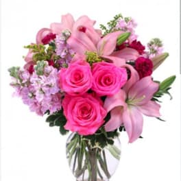 Pink roses and lilies arranged in a clear glass vase