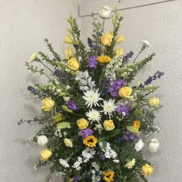 Tall standing floral spray with yellow, white, and purple flowers