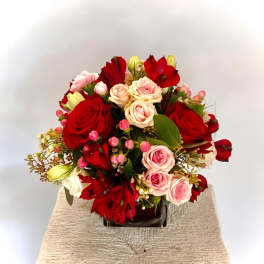Bouquet of red and pink roses with red blooms in a dark vase