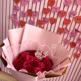 Bouquet of red and pink roses wrapped in pale pink paper