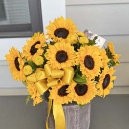 Sunflower bouquet in a gray vase with a yellow ribbon