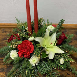 Holiday centerpiece with red candles, lilies, and red and white flowers