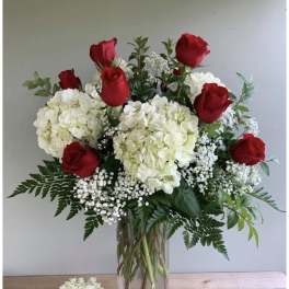 Red roses and white hydrangeas in a clear glass vase
