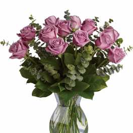 Arrangement of lavender roses with eucalyptus accents in a clear glass vase