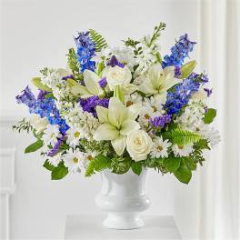 White and blue mixed flower arrangement in a white vase