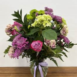 Pink rose and purple chrysanthemum bouquet in a glass vase with ribbon