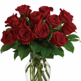 Dozen red roses arranged in a clear glass vase