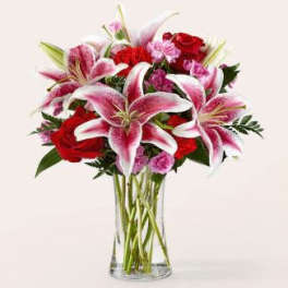 Bouquet of pink lilies and red roses in a clear glass vase