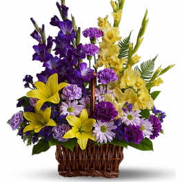 Basket arrangement of yellow lilies, purple gladiolus, carnations, and lavender daisy mums