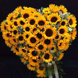 Heart-shaped sunflower arrangement with a ribbon bow on a dark background