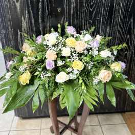 Pastel roses and baby's breath in a low arrangement on a stand