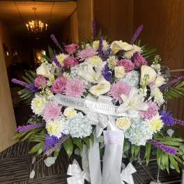 Large sympathy spray with pink, white, and purple flowers on a stand