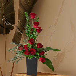Tall arrangement of red roses in a black vase