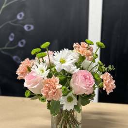 Pink and white flowers arranged in a clear glass vase