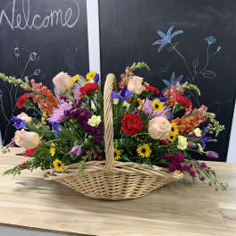 Mixed flowers arranged in a wicker basket on a table