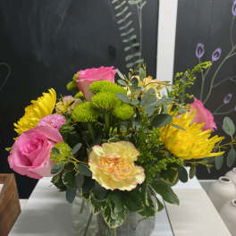 Bouquet of pink roses, yellow chrysanthemums, and a carnation in a glass vase