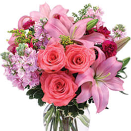 Pink roses and lilies arranged in a clear glass vase